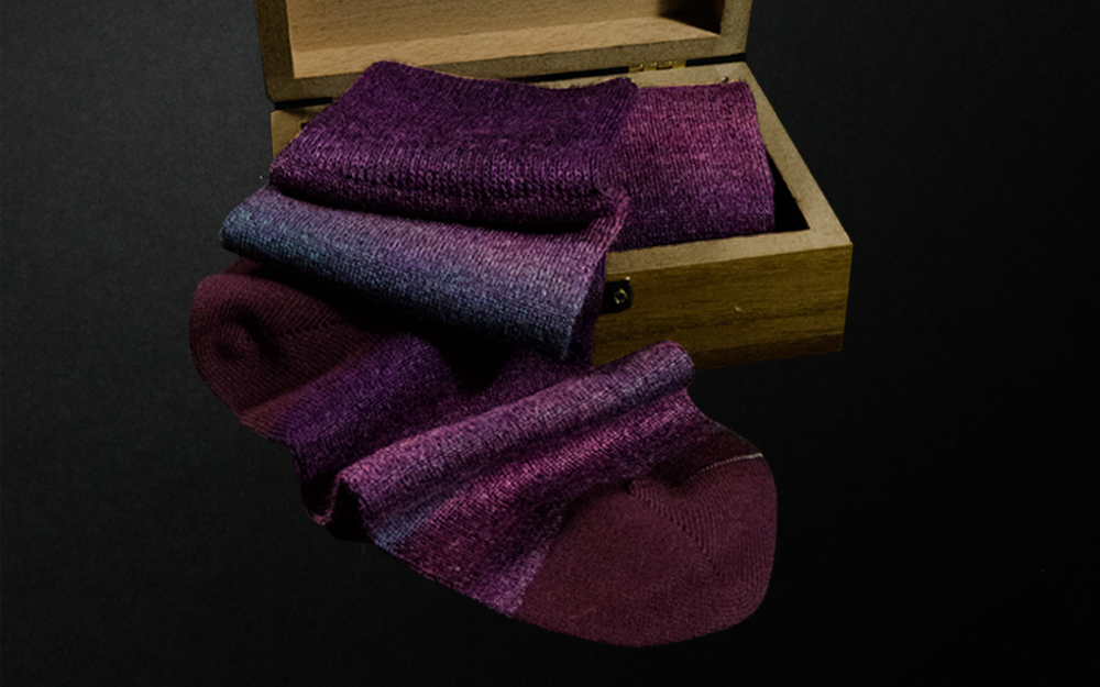 Purple custom socks presented in a wooden box